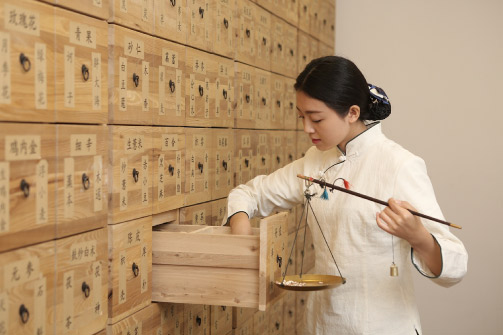 especialista-en-medicina-tradicional-china-seleccionando-hierbas-y-sosteniendo-una-balanza