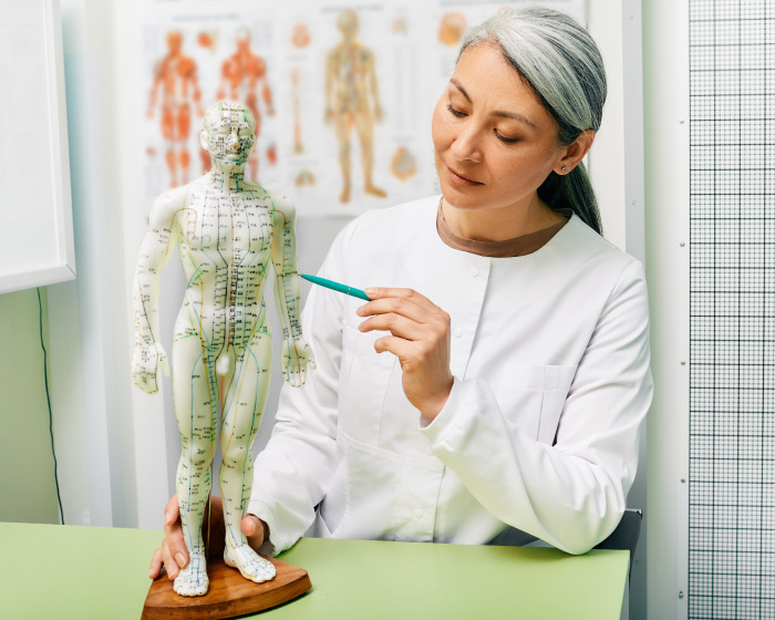 mujer-mostrando-puntos-sobre-el-modelo-de-acupuntura-del-cuerpo-humano