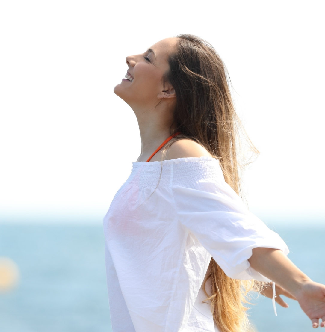 mujer-sonriente-con-los-brazos-abiertos-en-la-playa