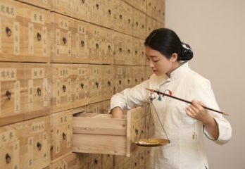 especialista-en-medicina-tradicional-china-seleccionando-hierbas-y-sosteniendo-una-balanza