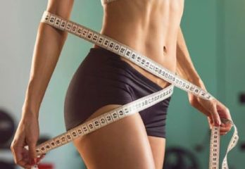 mujer-esbelta-delgada-de-pie-con-una-cinta-enrollada-en-el-cuerpo-nutricion-y-auriculoterapia